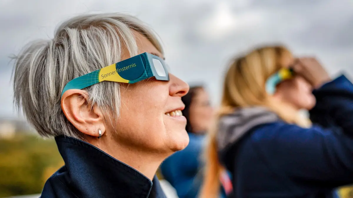 Partielle Sonnenfinsternis - Hamburg: ARCHIV - 24.10.2022, Hamburg: Eine Besucherin des Hamburger Planetariums betrachtet von der Aussichtsterasse aus mit Schutzbrille eine partielle Sonnenfinsternis. Die partielle Finsternis ist in Teilen Europas, Afrikas und Asiens zu sehen. (zu dpa: «Totale Sonnenfinsternis in Spanien - in Deutschland partiell sichtbar») Foto: Axel Heimken/dpa +++ dpa-Bildfunk +++