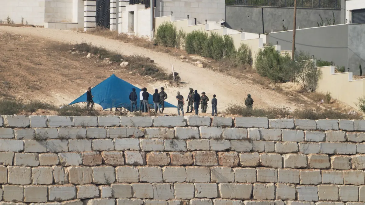 Nahostkonflikt - Westjordanland: 14.08.2026, Palästinensische Gebiete, Kusra: Israelische Soldaten evakuieren israelische Siedler, bevor sie deren Zelt abbauen; dieses befand sich vor einem von drei Häusern palästinensischer Familien, die im besetzten Dorf Kusra im Westjordanland – südlich von Nablus – seit sechs Tagen von Siedlern belagert werden. Foto: Majdi Mohammed/AP/dpa +++ dpa-Bildfunk +++
