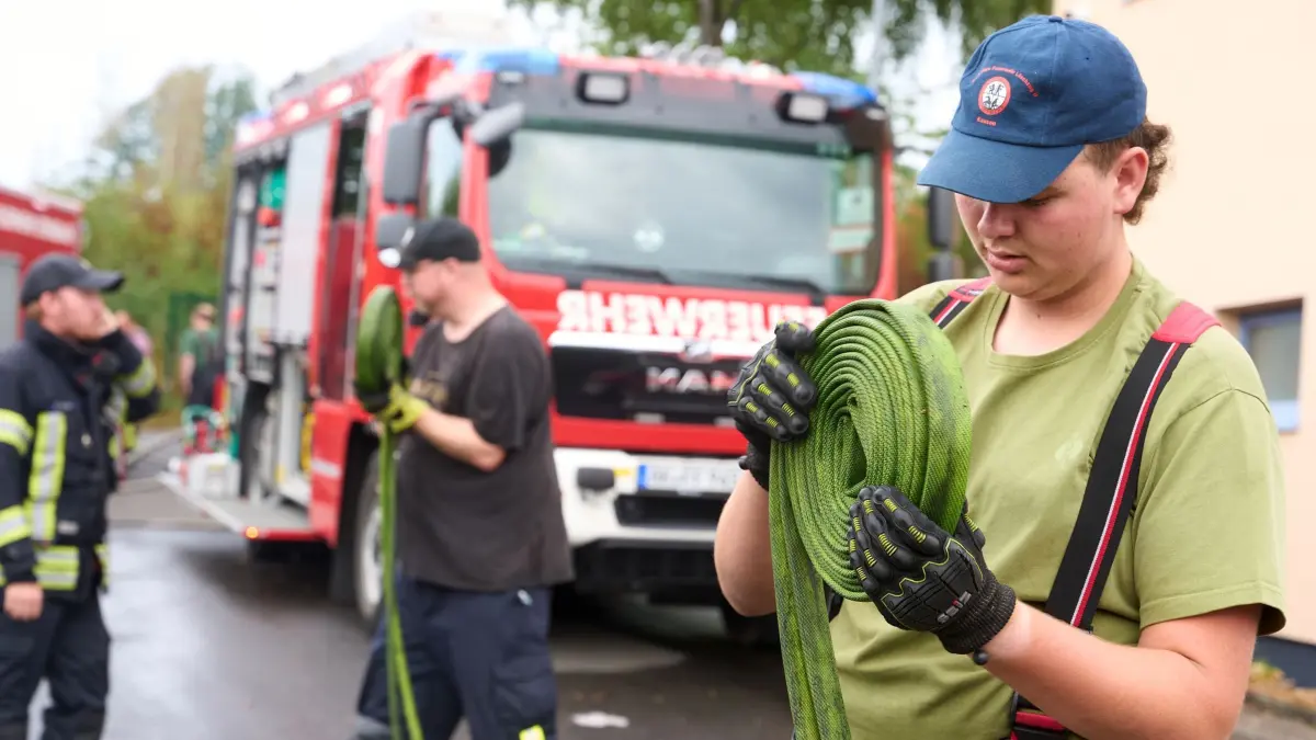 Waldbrand im Westerwald: 17.08.2026, Rheinland-Pfalz, Betzdorf-Gebhardshain: Feuerwehrleute rollen nach einem Waldbrand im Westerwald ihre Schläuche zusammen. Nach dem Waldbrand beim Ortsteil Gebhardshain läuft der Einsatz mit Nachlöscharbeiten weiter. Bei dem Brand kamen die Flammen bis auf 20 Meter an Häuser heran. Foto: Thomas Frey/dpa +++ dpa-Bildfunk +++