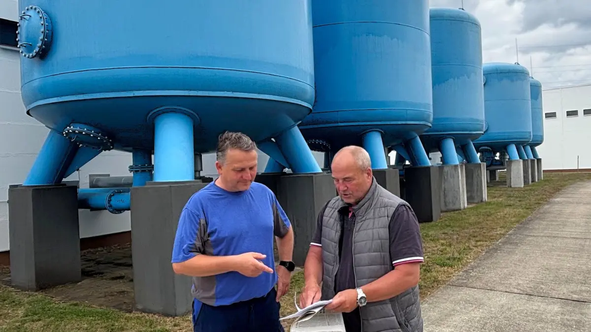 Auf dem Gelände des Wasserwerkes Oschätzchen stehen große, blaue Behälter. Die vorderen enthalten Filter für die Entmanganung des gehobenen Wassers. Dahinter steht die Enteisenung. Beim Blick auf die Zahlen stellen WAV‑Verbandsvorsteher Maik Hauptvogel (r.) und Heiko Pirschel, Meister Trinkwasserversorgung, eines fest: Die Trinkwasserversorgung im WAV-Gebiet ist auf lange Zeit sicher.