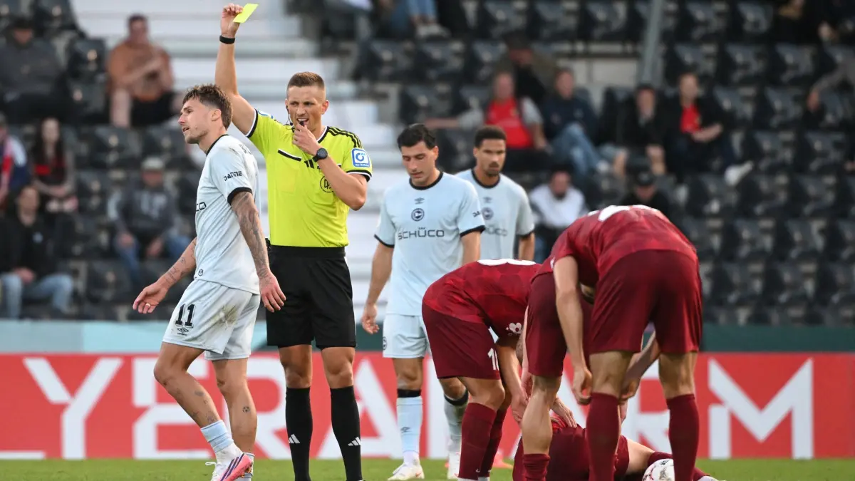 SG Sonnenhof Großaspach - Arminia Bielefeld: 22.08.2026, Baden-Württemberg, Aspach: Fußball, Männer: DFB-Pokal, SG Sonnenhof Großaspach - Arminia Bielefeld, 1. Runde in der WIRmachenDRUCK Arena. Schiedsrichter Felix Bickel (2.v.l.) zeigt Joel Grodowski (l) von Bielefeld die Gelbe Karte. Foto: Marijan Murat/dpa - WICHTIGER HINWEIS: Gemäß den Vorgaben der Bundesliga bzw. des DFB Deutscher Fußball-Bund ist es untersagt, in dem Stadion und/oder vom Spiel angefertigte Fotoaufnahmen in Form von Sequenzbildern und/oder videoähnlichen Fotostrecken zu verwerten bzw. verwerten zu lassen. +++ dpa-Bildfunk +++