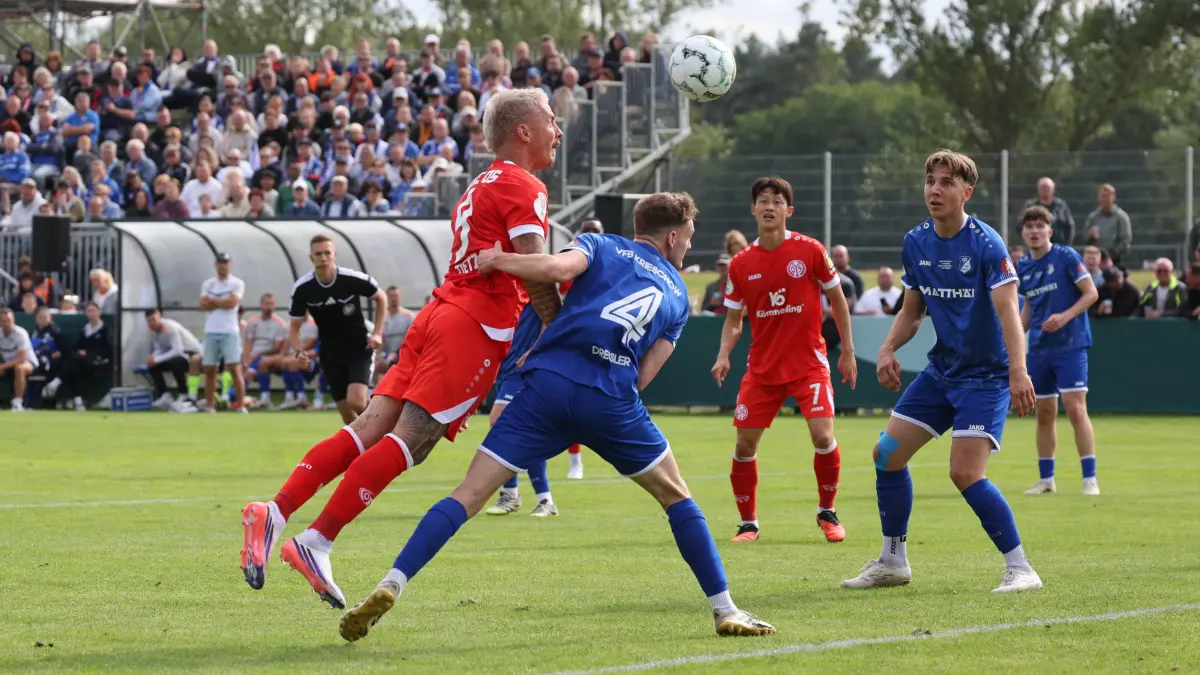 Fußball DFB-Pokal 2026/2027 1. Hauptrunde VfB Krieschow 1921 - 1. FSV Mainz 05: 21 Danny Viera Da Costa (Mainz), l. setzt sich gegen 4 Dressler, Bastian (Krieschow) und macht mit dem 3-0 für Mainz seinen Hattrick perfekt