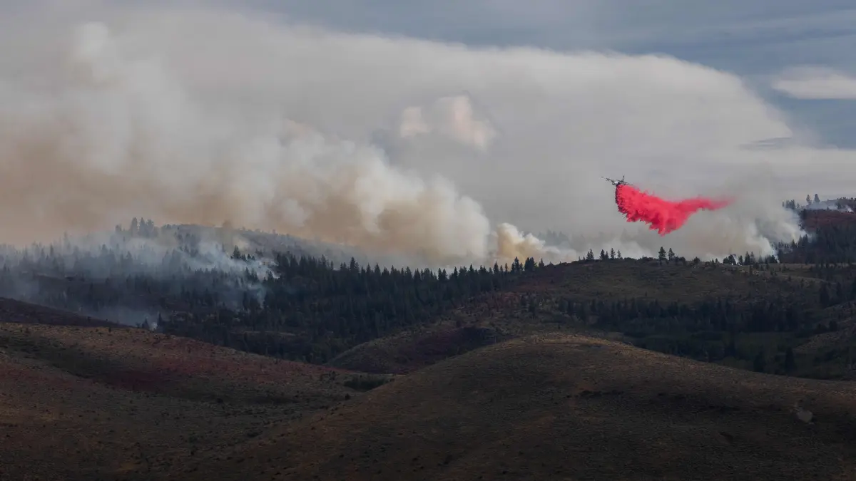 Hawk Fire Forces Thousands To Evacuate In Northern Nevada: RENO, NEVADA - AUGUST 23: A firefighting aircraft drops fire retardant during the Hawk Fire on August 23, 2026 in Reno, Nevada. The wildfire spread from the Sierra foothills towards Reno, forcing thousands to evacuate their homes. Officials said the fire was human-caused. Trevor Bexon/Getty Images/AFP (Photo by Trevor Bexon / GETTY IMAGES NORTH AMERICA / Getty Images via AFP)