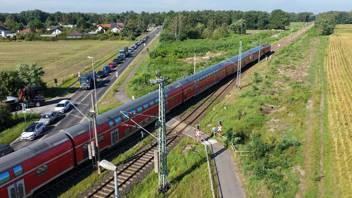 DB Zweites Gleis Vorb: Im Bild: Bahnübergang Kolkwitz
Luftaufnahme vom 25. August 2026
Der Bau des zweiten Gleises auf der Strecke zwischen Cottbus und Lübbenau steht unmittelbar bevor. Gleich hinter dem Bahnübergang Kolkwitz, Berliner Strasse wurden bereits Abholzarbeiten für den zweigleisigen Ausbau der Bahnstrecke Cottbus-Lübbenau durchgeführt.
Die Bahnstrecke zwischen Cottbus und Lübbenau bekommt ein zweites Gleis: Damit soll der Schienenverkehr zwischen Cottbus und Berlin zukünftig schneller und zuverlässiger werden.
Innerhalb von zwölf Monaten soll der neue Schienenabschnitt unter Vollsperrung fertig ausgebaut werden. Ab Dezember 2026 sollen die Bauarbeiten am Gleis samt Sperrung beginnen
Die ersten Bauarbeiten hatten schon im Jahr 2025 stattgefunden. Sie umfassten Umweltmaßnahmen und den Aufbau von Amphibien- und Reptilienschutzzäunen. Im Herbst 2025 begannen Baumfällungen entlang der Strecke, um Platz für die künftigen Gleise zu schaffen. Vor der Sperrung der Strecke zwischen Cottbus und Lübbenau müssen noch weitere Vorbereitungsmaßnahmen durchgeführt werden: Baustraßen, Baueinrichtungsflächen und temporäre Kabelkanäle zur Stromversorgung der Maschinen müssen errichtet werden.
Im Jahr 2027 laufen dann die Maßnahmen für den Bau des zweiten Gleises, die bis Ende des nächsten Jahres abgeschlossen werden sollen.
Zwischen der Lausitz und der Bundeshauptstadt wird dann ein Halbstundentakt möglich sein und auch die Kapazitäten für den Güterverkehr der Wirtschaft werden dadurch erhöht.