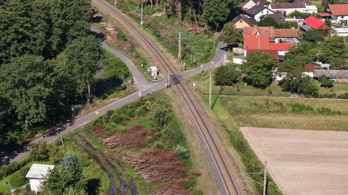 DB Zweites Gleis Vorb: Im Bild: Bahnstrecke entlang Dahlitz/ Teichlandschaft Kolkwitz/Glinzig
Luftaufnahme vom 25. August 2026
Der Bau des zweiten Gleises auf der Strecke zwischen Cottbus und Lübbenau steht unmittelbar bevor. Gleich hinter dem Bahnübergang Kolkwitz, Berliner Strasse wurden bereits Abholzarbeiten für den zweigleisigen Ausbau der Bahnstrecke Cottbus-Lübbenau durchgeführt.
Die Bahnstrecke zwischen Cottbus und Lübbenau bekommt ein zweites Gleis: Damit soll der Schienenverkehr zwischen Cottbus und Berlin zukünftig schneller und zuverlässiger werden.
Innerhalb von zwölf Monaten soll der neue Schienenabschnitt unter Vollsperrung fertig ausgebaut werden. Ab Dezember 2026 sollen die Bauarbeiten am Gleis samt Sperrung beginnen
Die ersten Bauarbeiten hatten schon im Jahr 2025 stattgefunden. Sie umfassten Umweltmaßnahmen und den Aufbau von Amphibien- und Reptilienschutzzäunen. Im Herbst 2025 begannen Baumfällungen entlang der Strecke, um Platz für die künftigen Gleise zu schaffen. Vor der Sperrung der Strecke zwischen Cottbus und Lübbenau müssen noch weitere Vorbereitungsmaßnahmen durchgeführt werden: Baustraßen, Baueinrichtungsflächen und temporäre Kabelkanäle zur Stromversorgung der Maschinen müssen errichtet werden.
Im Jahr 2027 laufen dann die Maßnahmen für den Bau des zweiten Gleises, die bis Ende des nächsten Jahres abgeschlossen werden sollen.
Zwischen der Lausitz und der Bundeshauptstadt wird dann ein Halbstundentakt möglich sein und auch die Kapazitäten für den Güterverkehr der Wirtschaft werden dadurch erhöht.