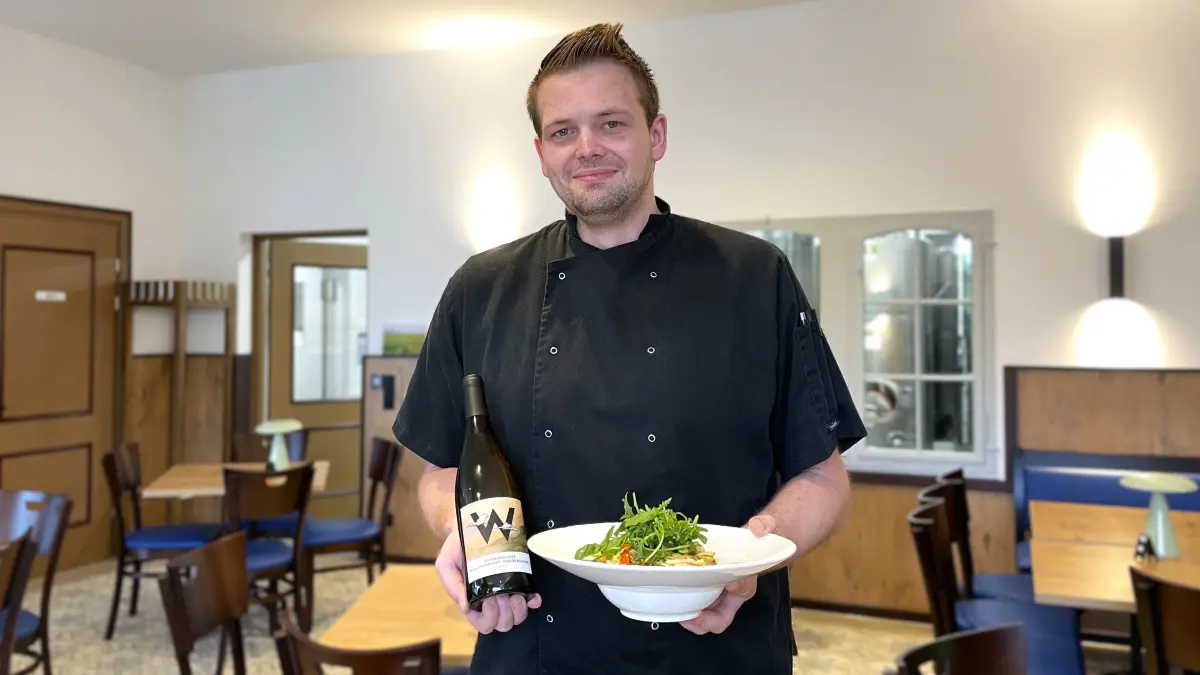Erik Jakisch, Koch in der Vinothek Wolkenberg in Welzow, am 17.08.2026 mit einem Teller Tagiatelle mit Pfifferlingen und einer Flasche Wolkenberg-Wein