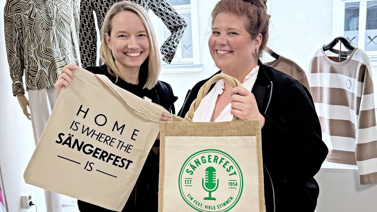 Anja Otto (l.) und Maria Koch vom Sängerfestverein versprechen: Mit den neuen Werbeartikeln zum Finsterwalder Sängerfest kann man nicht nur einkaufen gehen.