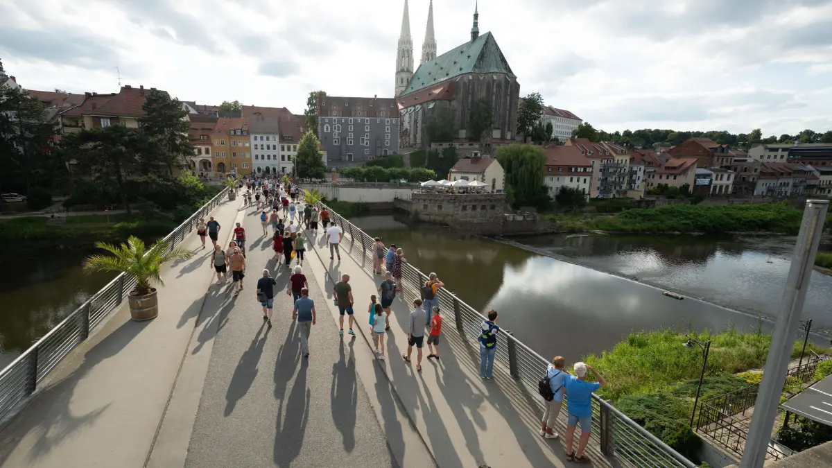 Passanten gehen beim Internationalen Straßentheaterfestival ViaThea über die Altstadtbrücke und überqueren den Grenzfluss Neiße zwischen Polen und Deutschland.