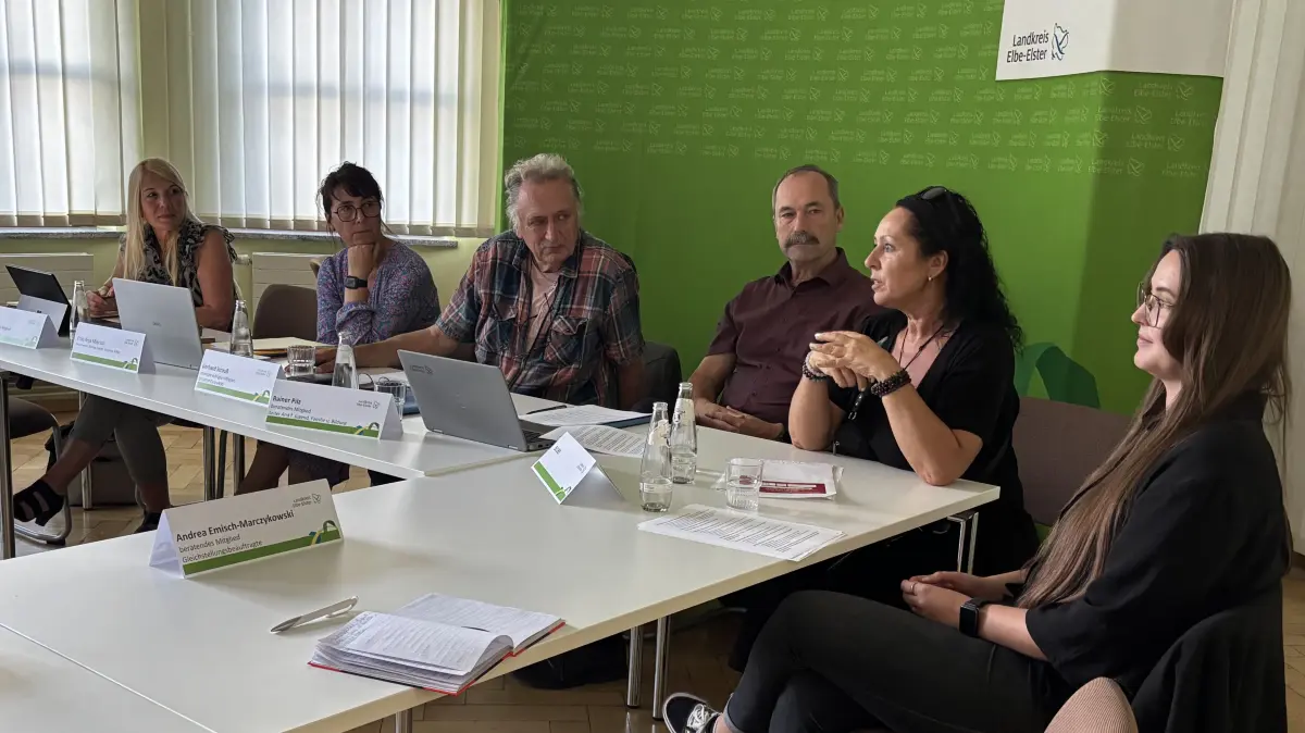 Im Jugendhilfeausschuss in Herzberg/Elster stellen Marleen Kosmann (2. von rechts) und Laura Heinig (rechts) die Arbeit der Ombudsstelle vor — neben ihnen sitzen Jugendamtsleiter Rainer Pilz, Ausschussvorsitzender Gerhard Strauß (Mitte) und weitere Mitglieder. Die Runde zeigt, wie ein einzelner Fall die Frage aufwirft, ob das System Familien noch auffangen kann.