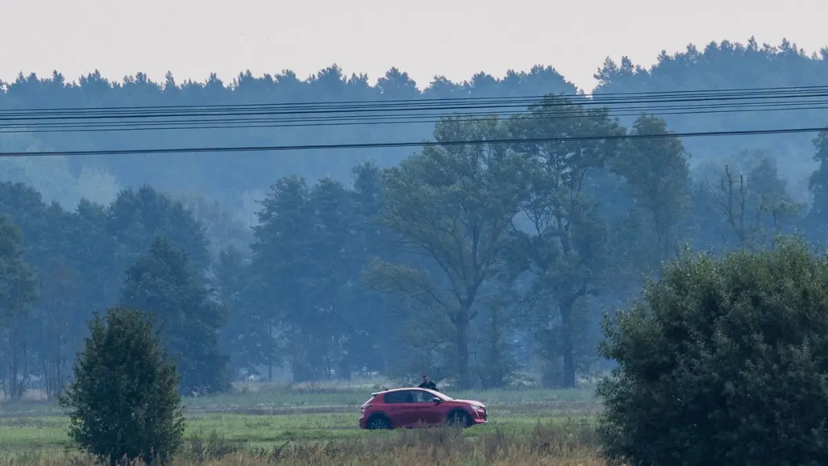 Nach Angriffen auf Stromnetz in Südbrandenburg: 03.09.2026, Brandenburg, Preilack: Ein über eine Wiese im Sperrkreis fahrender Pkw wird von einem Polizeibeamten aufgehalten. Nach der Sabotage am Stromnetz in Südbrandenburg führt die Polizei die großräumige Durchsuchung am Ereignisort heute weiter. Straßen bleiben gesperrt. Foto: Frank Hammerschmidt/dpa +++ dpa-Bildfunk +++