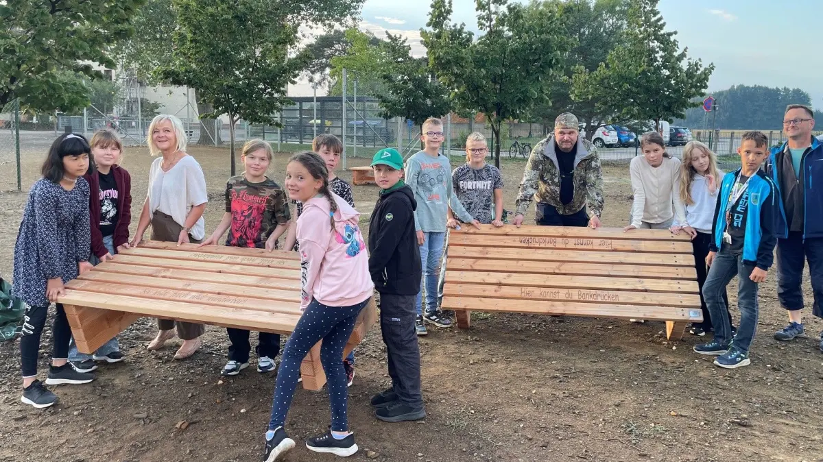 Die neuen Schulbänke aus Douglasienholz für den Pausenhof an der Grundschule in Wahrenbrück. Marcus Böhme (hinten Mitte) hat sie sehr zur Freude von Schulleiterin Alexandra Bauer (3.v.l.) und Schülern gebaut.