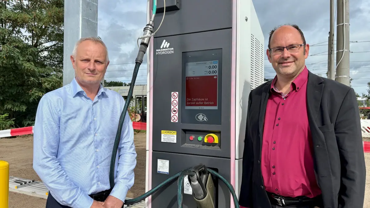 Cottbusverkehr-Geschäftsführer Ralf Thalmann (r.) und Betriebsleiter Dirk Jäkisch stehen an der Zapfsäule (Dispenser) der neuen Wasserstoff-Tankstelle auf dem Betriebshof in Cottbus-Schmellwitz. Noch fehlt der Elektrolyseur, bevor die Anlage in Betrieb gehen kann.