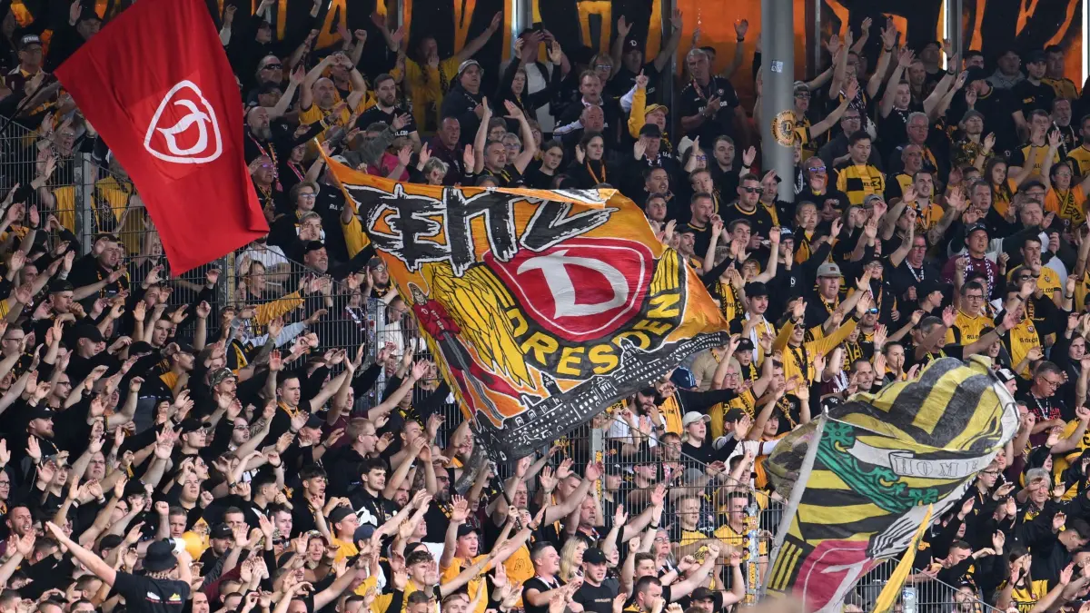 Eintracht Braunschweig - SG Dynamo Dresden: 12.09.2026, Niedersachsen, Braunschweig: Fußball, Männer, 2. Bundesliga, Eintracht Braunschweig - SG Dynamo Dresden, 5. Spieltag, Eintracht-Stadion: Fans von SG Dynamo Dresden zeigen Fahnen und jubeln auf der Tribüne. Foto: Swen Pförtner/dpa - WICHTIGER HINWEIS: Gemäß den Vorgaben der Bundesliga bzw. des DFB Deutscher Fußball-Bund ist es untersagt, in dem Stadion und/oder vom Spiel angefertigte Fotoaufnahmen in Form von Sequenzbildern und/oder videoähnlichen Fotostrecken zu verwerten bzw. verwerten zu lassen. +++ dpa-Bildfunk +++