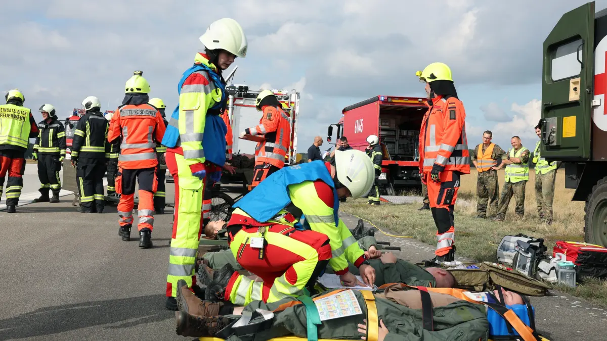 Bei der Flugunfall‑Übung in Holzdorf bei Schönewalde/Elster versorgen Rettungskräfte gemeinsam mit der Bundeswehr mehrere „Verletzte“ und trainieren die Übergabe zwischen den Einheiten. Dabei offenbart die Übung eine Schwachstelle, die im Ernstfall entscheidend wäre.