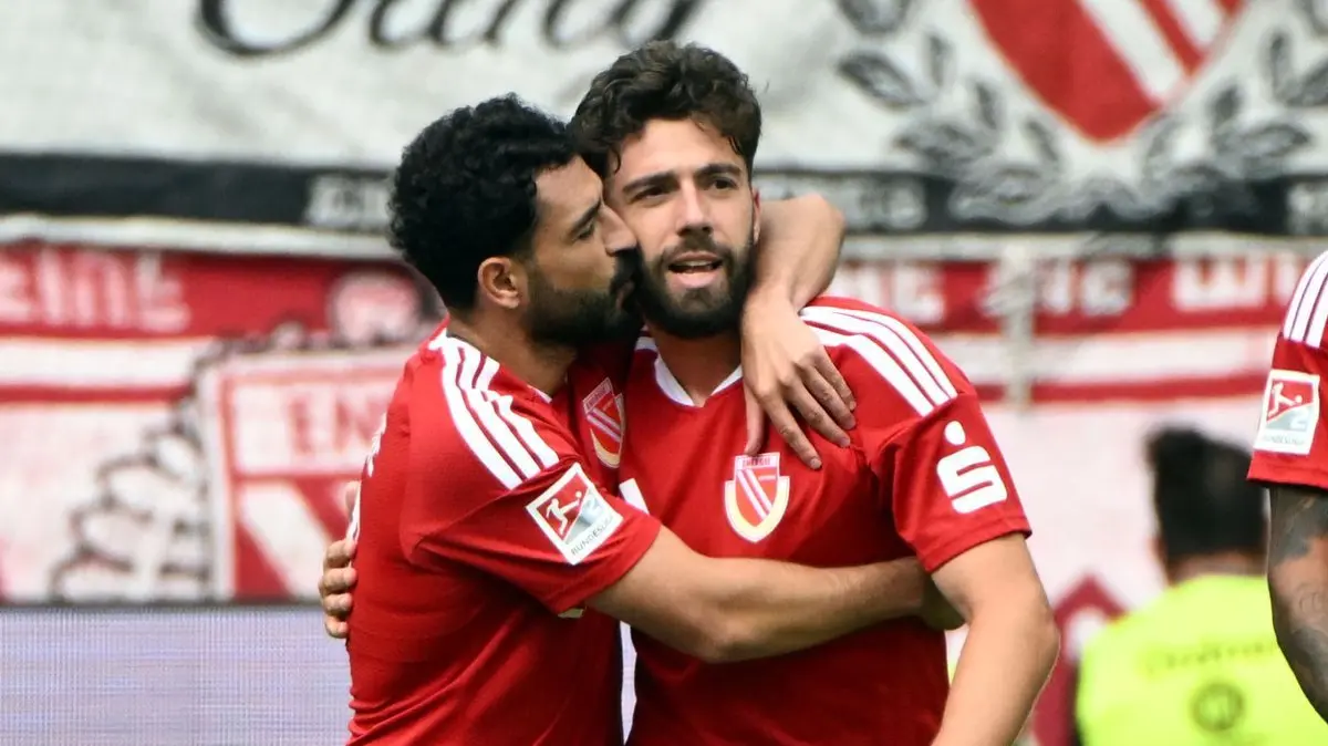 Karlsruher SC - Energie Cottbus: 13.09.2026, Baden-Württemberg, Karlsruhe: Fußball, Männer, 2. Bundesliga, 5. Spieltag, Karlsruher SC - Energie Cottbus, BBBank Wildpark: Die Cottbuser Tolcay Cigerci (l) und Dominik Pelivan bejubeln den Treffer zum 0:2 durch Dominik Pelivan. Foto: Uli Deck/dpa - WICHTIGER HINWEIS: Gemäß den Vorgaben der Bundesliga bzw. des DFB Deutscher Fußball-Bund ist es untersagt, in dem Stadion und/oder vom Spiel angefertigte Fotoaufnahmen in Form von Sequenzbildern und/oder videoähnlichen Fotostrecken zu verwerten bzw. verwerten zu lassen. +++ dpa-Bildfunk +++