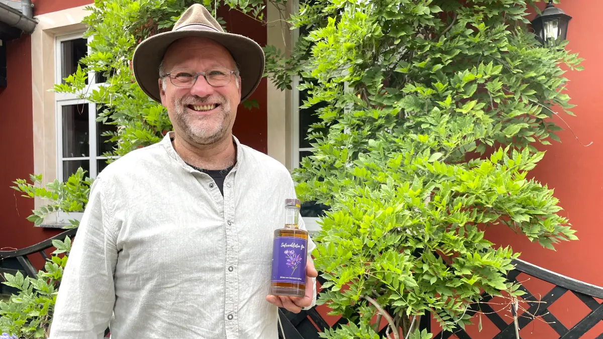 Wolfgang Mattheus von Lausiko's hält eine Flasche Safranblüten-Gin am 7.9.2026 in Hermsdorf-Jannowitz in der Hand.