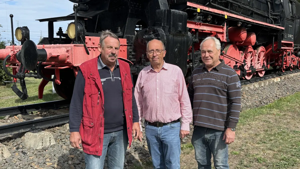 Von links: Markus Winter, Rainer Rahnfeld und das ehrenamtliche Mitglied des Fördervereins, Klaus‑Peter Drasdo, stehen vor der Dampflok auf dem Gelände des Eisenbahnmuseums Falkenberg/Elster.