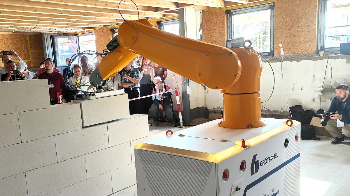 Der Wallbot fügt unter großen Zuschauerinteresse einen weiteren Stein in die Mauer ein.
