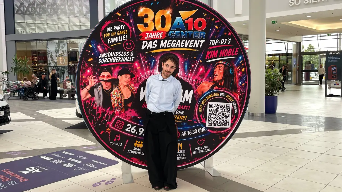 Bei der Geburtstagsfeier im A10 Center tritt ein bekannter Techno DJ aus den 90er Jahren auf. Julien Pree dreht vor dem Aufsteller an der Kundeninformation sein Video.