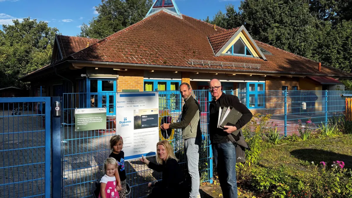 Sanierung der Kita Lindenblüte in Ruhland: Im Beisein von zwei Kitakindern bringen Einrichtungsleiterin Yvonne Förster, Bauleiter Stephan Hain und Architekt Martin Tiede das Bauschild an.