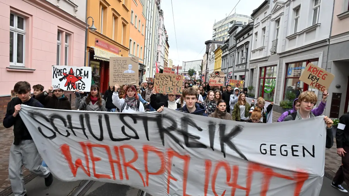 Schulstreik Wehrpflicht Sept 2026: Schulstreik gegen die Wehrpflicht auch in Cottbus
Am bundesweiten Aktionstag gegen die Wehrpflicht beteiligten sich am Freitag auch rund 250 Schülerinnen und Schüler sowie erwachsene Unterstützerinnen und Unterstützer von Cottbuser Schulen. Hier gab es um 11.30 Uhr Eine Kundgebung auf dem Altmarkt, also mitten in der Unterrichtszeit und anschließend eine Demonstration. Diese führte zum Niedersorbischen Gymnasium, zum Max-Steenbeck-Gymnasium, zum Piccolo Theater auf dem Erich Kästner Platz sowie zum Platz Am Stadtbrunnen und zurück zum Altmarkt. Es war der vierte Aktionstag der Initiative, im Mai kamen nach Angaben der Organisatoren rund 200 Menschen auf dem Altmarkt zusammen.
Die Initiative wendet sich gegen die Vorbereitungen für eine flächendeckende Wehrpflicht und gegen die weitere Umsetzung des Wehrdienstgesetzes. Als Beispiel führt sie den Start der Musterungen an, der früher komme als angekündigt. Die verpflichtenden Musterungen seien erst ab Juli 2027 angekündigt.
Der 1. Juli 2027 stand in der Begründung des Wehrdienstmodernisierungsgesetzes, aus dem Gesetzestext selbst wurde der Satz kurz vor der Verabschiedung gestrichen. Das Gesetz gilt seit dem 1. Januar 2026, seither mustern die Karrierecenter bereits. Das Verteidigungsministerium hält das für jedoch rechtlich zulässig. Der Fragebogen zur Wehrerfassung geht seit Anfang 2026 an alle Männer ab Jahrgang 2008 und muss beantwortet werden, der Wehrdienst selbst bleibt freiwillig.
