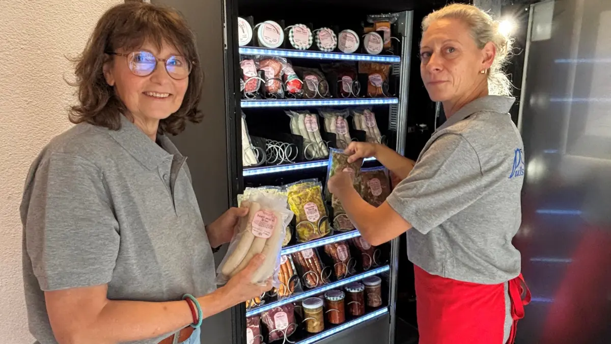 Martina Glowacki (l.), Geschäftsführerin der Hirschfeld Agrar GmbH, und Fleischfachverkäuferin Doreen Reiche demonstrieren hier das Auffüllen des Automaten im Eingangsbereich zur Landfleischerei in Hirschfeld.