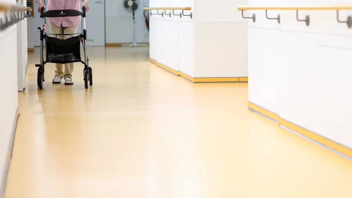 Seniorenheim: ARCHIV - 25.06.2026, Nordrhein-Westfalen, Grefrath: Eine ältere Frau geht mit einem Rollator über einen Flur in einem Seniorenheim. (zu dpa: «Regierungskreise: Kabinett beschließt Pflegereform») Foto: Christoph Reichwein/dpa +++ dpa-Bildfunk +++