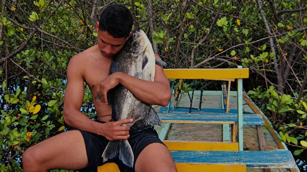 In "O Peixe" (Der Fisch) von Jonathas de Andrade hält ein brasilianischer Fischer seinen Fang. Der Film ist Teil der Doppel-Ausstellung "Der grelle Schein der Ränder“ inCottbus und Bad Muskau.