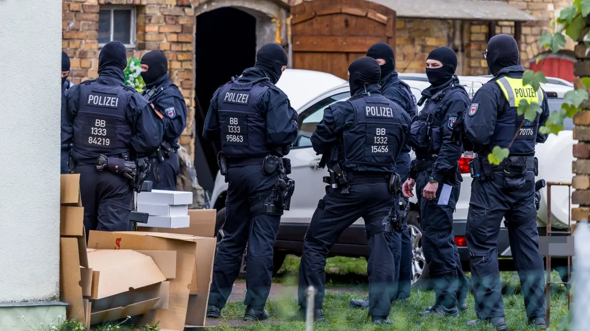 SEK-Einsatz in Schwarzheide-Ost: Vermummte Spezialkräfte der Polizei sichern das Grundstück während der Durchsuchungsmaßnahmen ab.