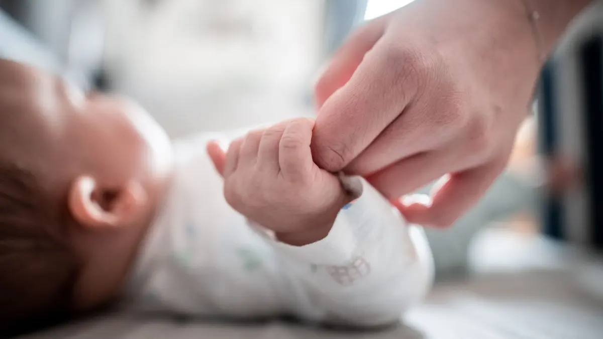 Ein Baby klammert sich an den Finger seiner Mutter: ARCHIV - Wie soll das Baby heißen? Ob ein Name beliebt oder eher ungewöhnlich ist, erfahren Eltern beim Studium von Namenshitlisten. (zu dpa: «Klingt schön, passt er aber auch? Die Tücken der Namenswahl») Foto: Fabian Strauch/dpa - Honorarfrei nur für Bezieher des dpa-Themendienstes +++ dpa-Themendienst +++