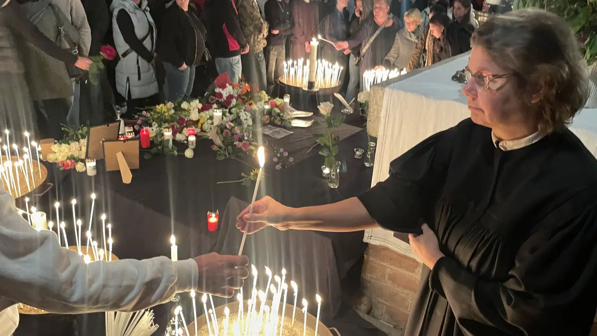 Pfarrerin Constanze Werstatt reicht das Kerzenlicht weiter. Gemeinsam mit Pfarrer Christoph Brust, Sophia Grothmann von Theresa von Avila Berlin Nordost und Bischof Christian Stäblein gestaltet sie die Trauerzusammenkunft in der Bernauer St.-Marien-Kirche.
