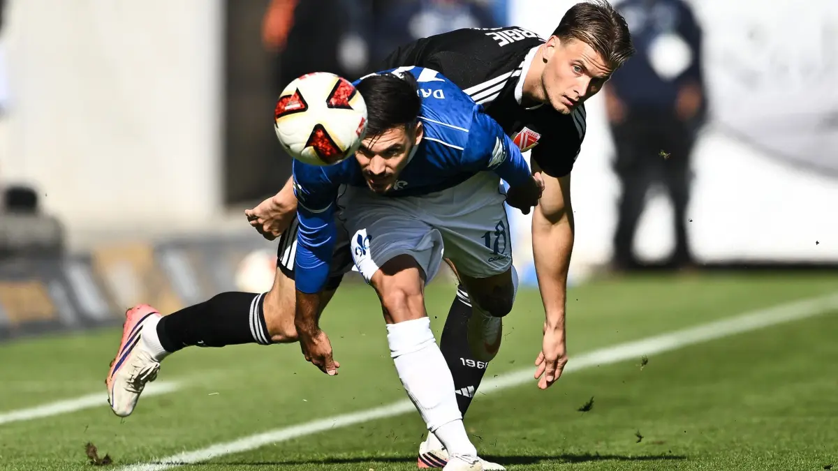 Darmstadt 98 - Energie Cottbus: 10.10.2026, Hessen, Darmstadt: Fußball, Männer: 2. Bundesliga, Darmstadt 98 - Energie Cottbus, 7. Spieltag, Merck-Stadion am Böllenfalltor. Moritz Hannemann (Energie Cottbus, hinten) und Raoul Petretta (SV Darmstadt 98) kämpfen um den Ball. Foto: Florian Wiegand/dpa - WICHTIGER HINWEIS: Gemäß den Vorgaben der Bundesliga bzw. des DFB Deutscher Fußball-Bund ist es untersagt, in dem Stadion und/oder vom Spiel angefertigte Fotoaufnahmen in Form von Sequenzbildern und/oder videoähnlichen Fotostrecken zu verwerten bzw. verwerten zu lassen. +++ dpa-Bildfunk +++