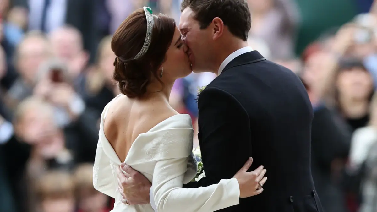 Prinzessin Eugenie und ihr Ehemann Jack Brooksbank küssen sich nach ihrer Hochzeit. Der tiefe Rückenausschnitt sorgte seinerzeit für Aufsehen, weil Eugenie damit eine Narbe am Rücken offen zeigte.