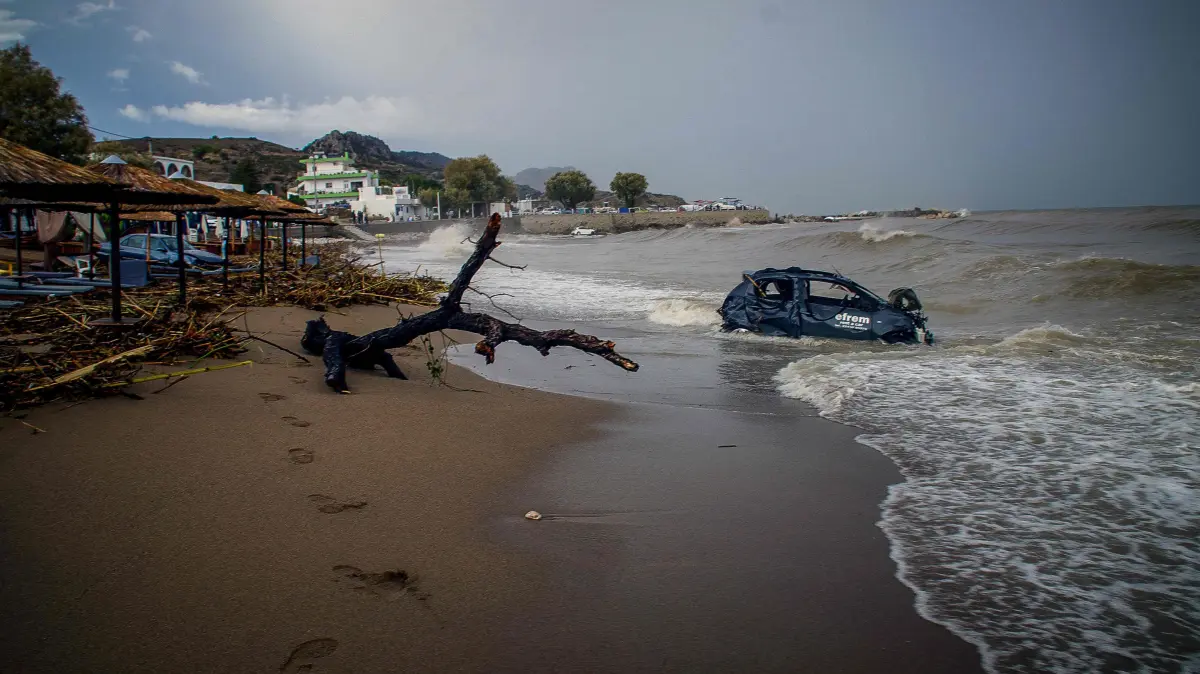 GREECE-WEATHER-CLIMATE-FLOODS: A car swept away by floodwaters lies on a beach as torrential rain and storms hit the Dodecanese, in the area of Stegna, near the village of Archangelos, on the Greek island of Rhodes on October 14, 2026. A 62-year-old man died in the area after his car was swept into the sea, authorities said, as the mayor requested that the island be declared in a state of emergency. (Photo by Eurokinissi / AFP)