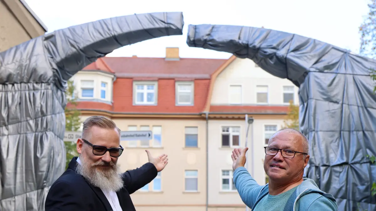 KWG-Geschäftsführer Tobias Dorn (l.) und Intendant Daniel Ris stehen vor dem verhüllten Torbogen an der Theaterpassage in Senftenberg.