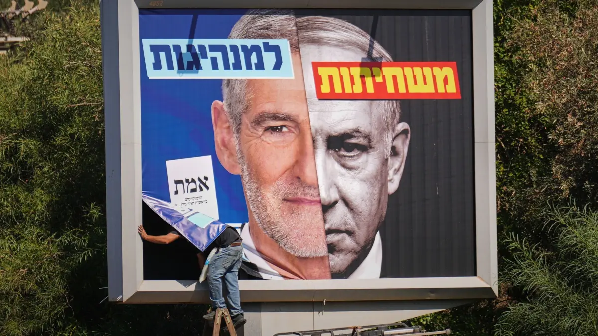 Vor den Parlamentswahlen in Israel: 19.10.2026, Israel, Tel Aviv: Ein Arbeiter bringt ein Wahlplakat der Demokratischen Partei an, auf dem deren Vorsitzender Yair Golan (l) neben einem Bild des israelischen Ministerpräsidenten Benjamin Netanjahu (r) zu sehen ist. Der hebräische Slogan lautet: «Von der Korruption zur Führung.». Israel wählt am 27.10.2026 ein neues Parlament. Foto: Ariel Schalit/AP/dpa +++ dpa-Bildfunk +++