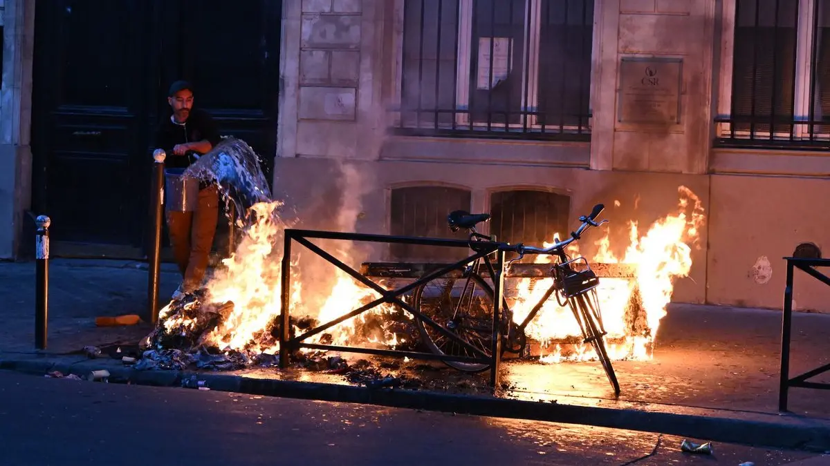 Ein Mann versucht in Paris, während der Zusammenstöße zwischen Demonstranten und Polizeibeamten ein Feuer zu löschen.