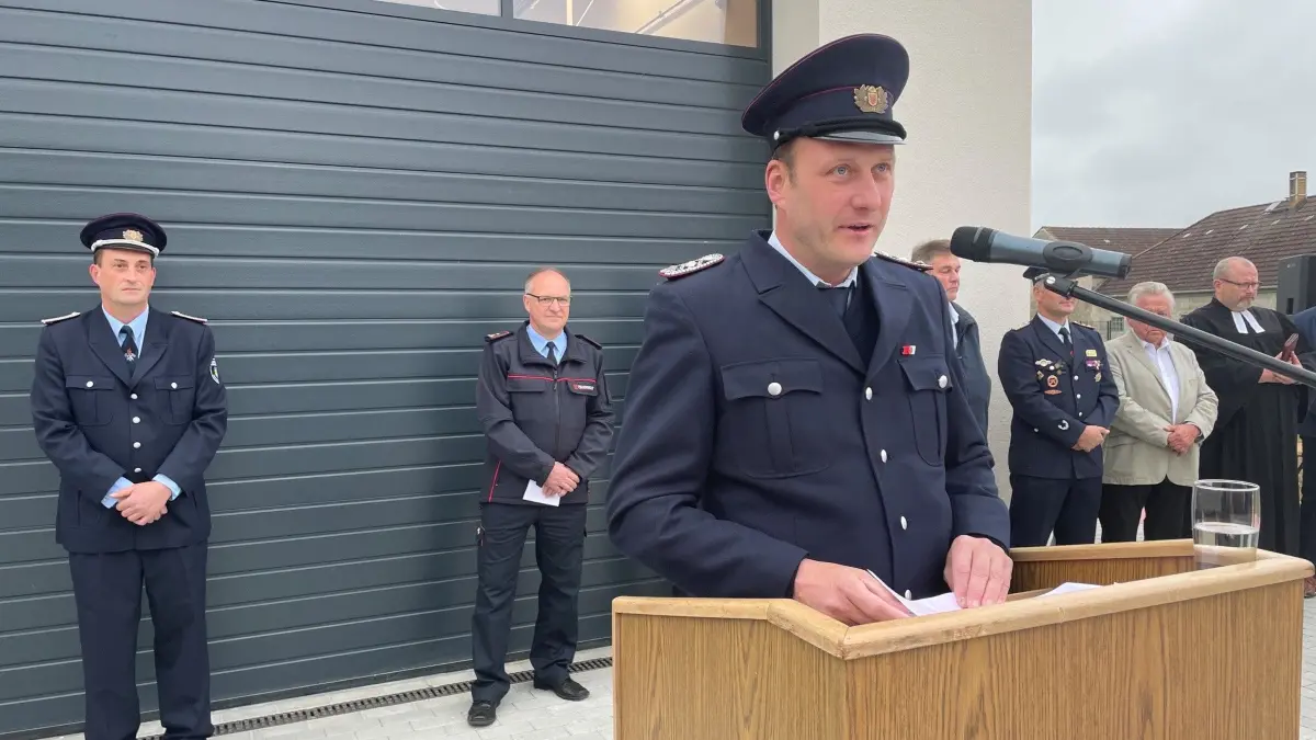 Christian Lehmann, am Pult, ist froh, nach dem jahrelangen Kampf endlich das Gerätehaus übernehmen zu können. Doch weitere Aufgaben warten noch. Hinten links sind Ortswehrführer Stefan König und daneben Torsten Lehnig, seit Juni 2026 der Stadtbrandmeister von Sonnewalde, begeistert bei der Zeremonie.