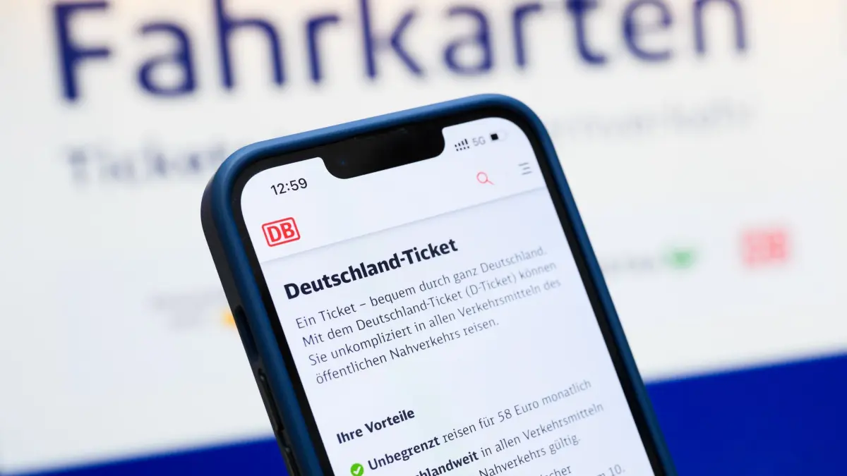Deutschlandticket: Eine Person hält ein Smartphone in der Hand, auf dessen Display eine Information zum Kauf des Deutschlandtickets zu sehen ist, während sie vor einem Fahrkartenautomaten steht. (zu dpa: «Neues digitales Ticket soll Bus- und Bahnfahren vereinfachen»)
