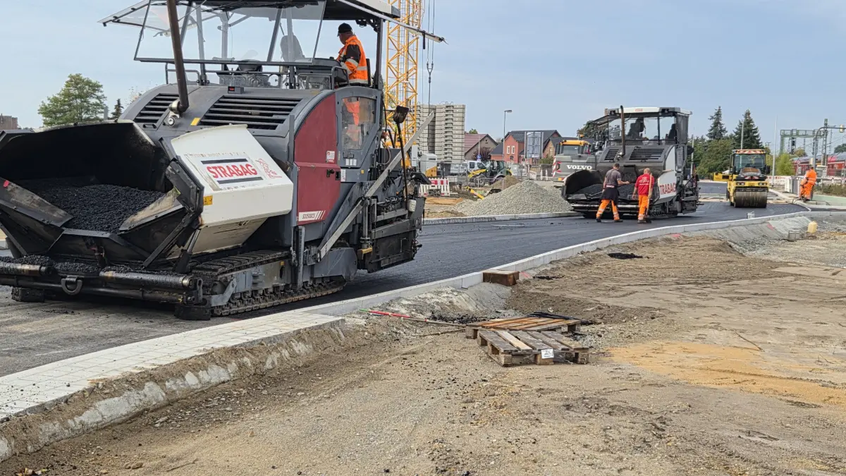 Mehrere Asphaltfertiger werden eingesetzt, um den Verkehrsknoten Nordkopf komplett mit einer Deckschicht zu versehen. Im Bild die Zufahrt vom Kreisverkehr in der Neustadt zur Straßenüberführung für die L49 parallel zur Gleisstrecke.
