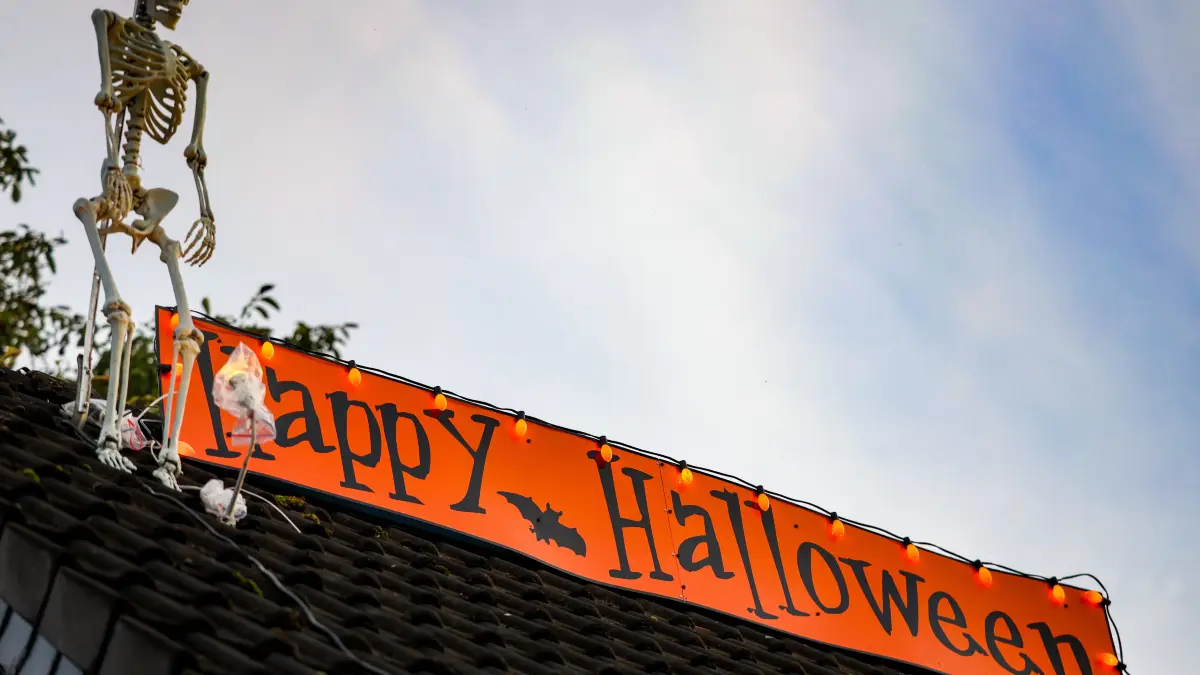 Auf dem Dach des «Halloween-Hauses» ist ein Schild mit der Aufschrift „Happy Halloween“ neben einem Plastik-Skelett zu sehen. +++ dpa-Bildfunk +++