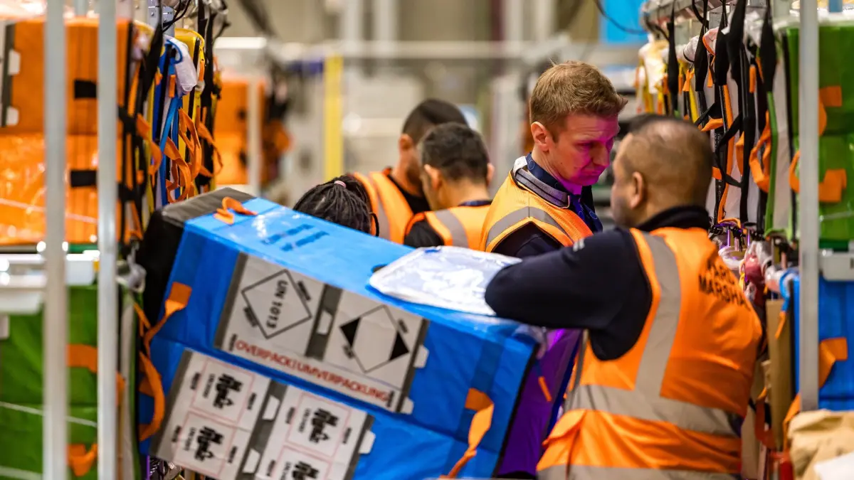 Neues Amazon-Verteilzentrum in Cottbus: 22.10.2026, Brandenburg, Cottbus: Mitarbeiter sortieren im Verteilzentrum Warensendungen in Regale. Ende September startete in Cottbus ein neues Verteilzentrum. Nach Angaben des Unternehmens sind damit vor Ort rund 70 Arbeitsplätze entstanden. Hinzu kämen noch an die Fahrer bei Lieferpartnern. In der rund 7700 Quadratmeter großen Halle sollen künftig bis zu 25.000 Pakete pro Tag bearbeitet werden. Foto: Frank Hammerschmidt/dpa - Honorarfrei nur für Bezieher des Dienstes ZB-Funkregio Ost +++ ZB-FUNKREGIO OST +++