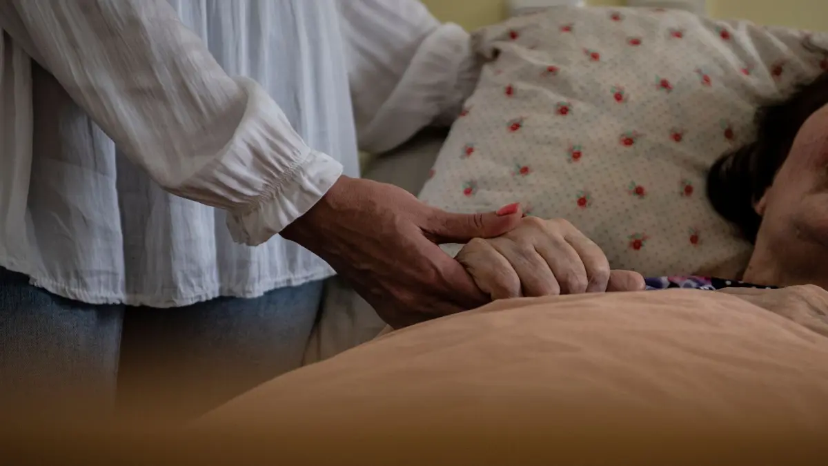 Pflegeheimkosten deutlich gestiegen: In einem Pflegeheim hält eine Frau die Hand einer Pflegebedürftigen. (zu dpa: «Neue Leitlinie sieht vertieften Umgang mit Sterbewunsch vor»)
